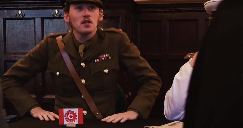 A leader in a military uniform sits at a table with a small flag, and another figure in white is partly visible on the right; no date or time information appears onscreen.