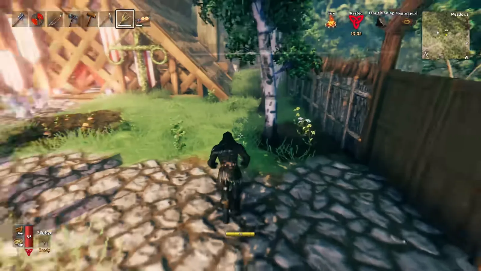 Valheim base perimeter with a wooden plank wall and fence beside a paved path
